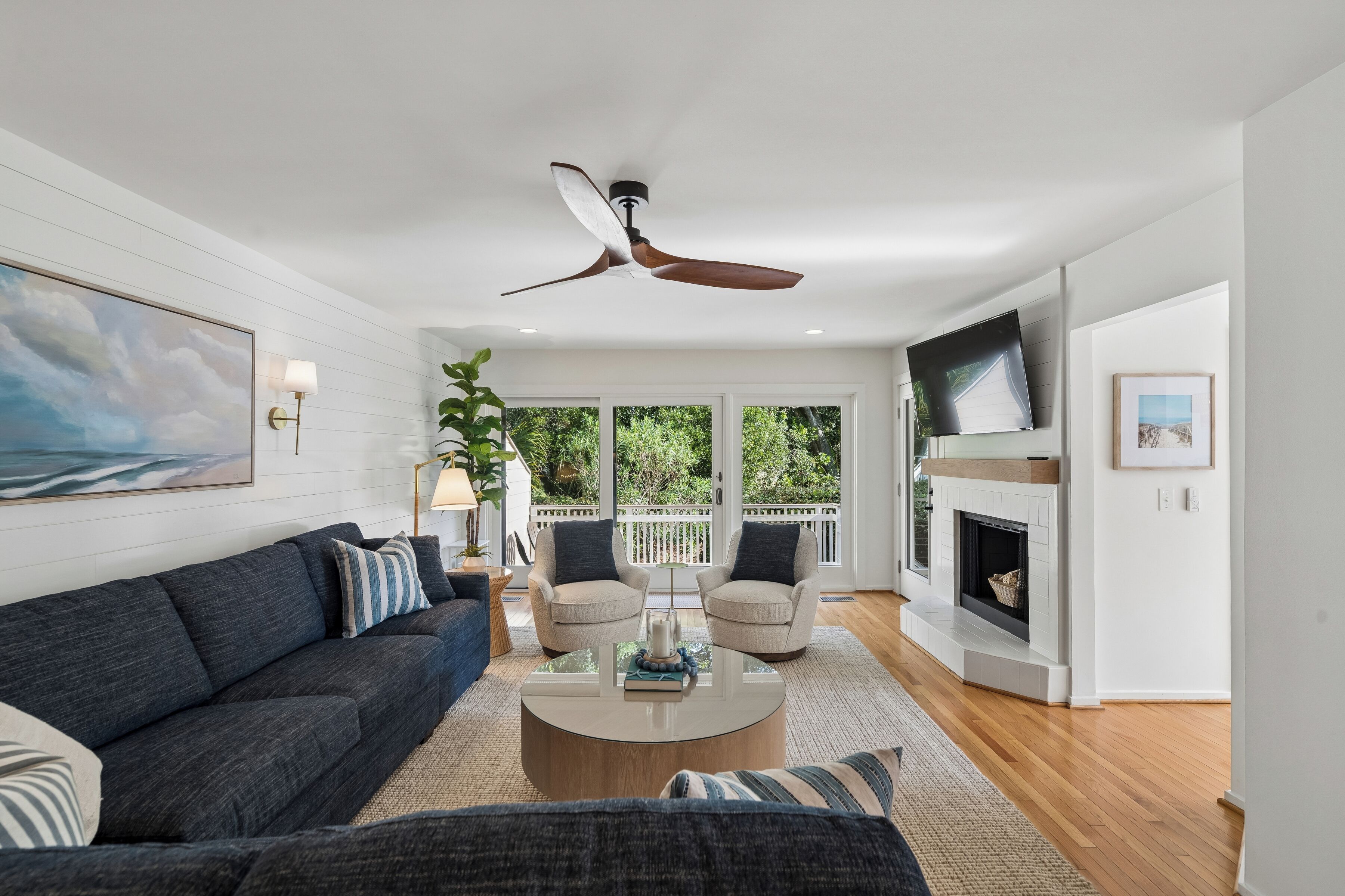 A modern living room with a dark sofa, a round coffee table, a beige armchair, and a fireplace.