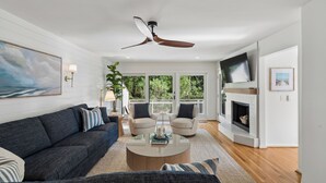 A modern living room with a dark sofa, a round coffee table, a beige armchair, and a fireplace.