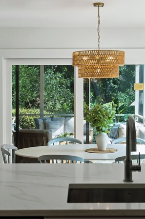 Une cuisine moderne avec un coin repas, de grandes fenêtres et un luminaire suspendu.