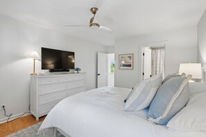 A bedroom with a bed, a dresser, a television, and a ceiling fan.