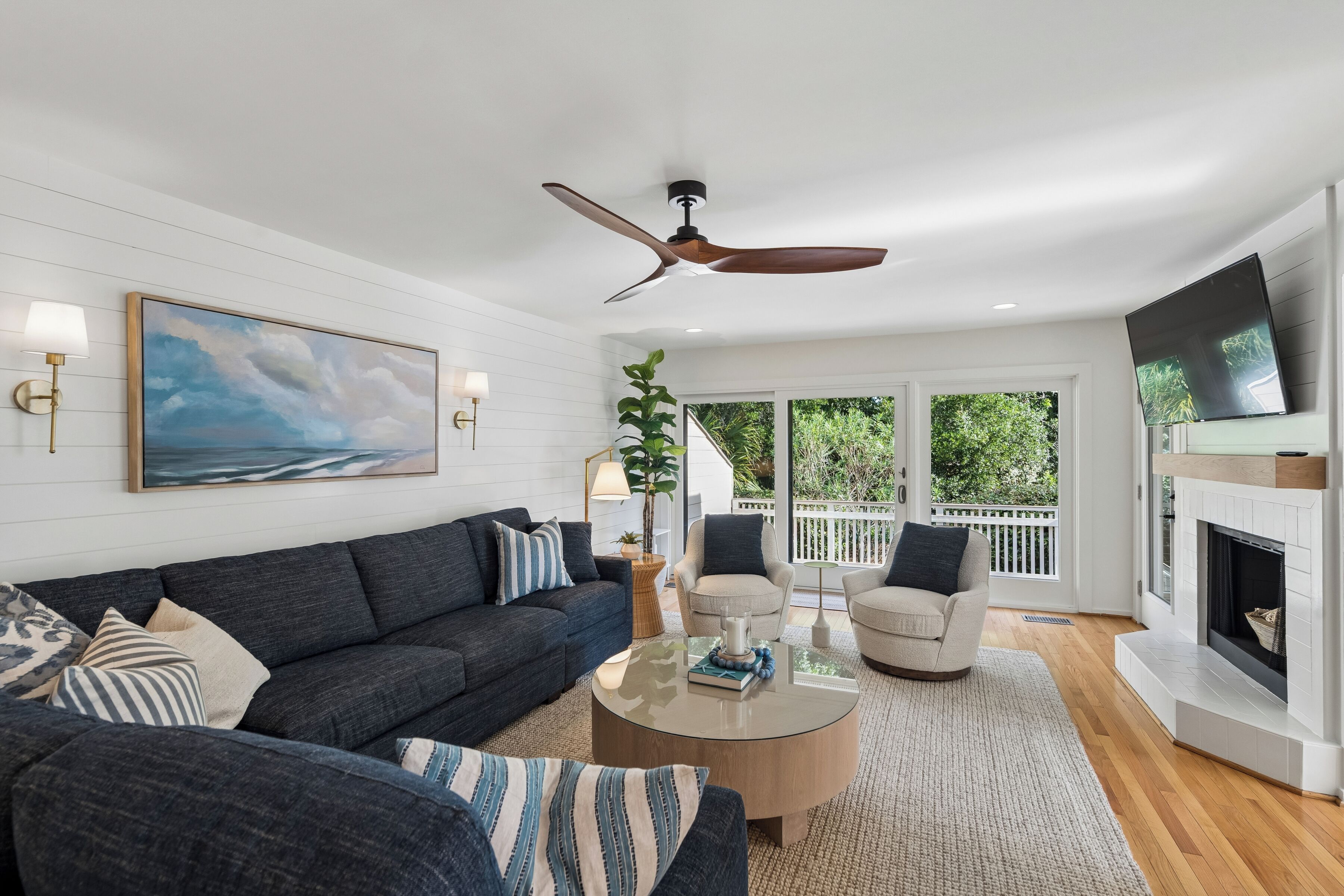 A modern living room with a dark grey sofa, a round coffee table, and a ceiling fan.