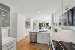 A modern kitchen with white cabinetry, a dishwasher, and a stove.