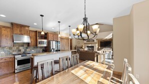 A modern kitchen with wooden cabinets, a large island, stainless steel appliances, and a chandelier. - Half-Mile to Keystone Base Area! Incredible Slope Views, Private Hot Tub (Keystone)