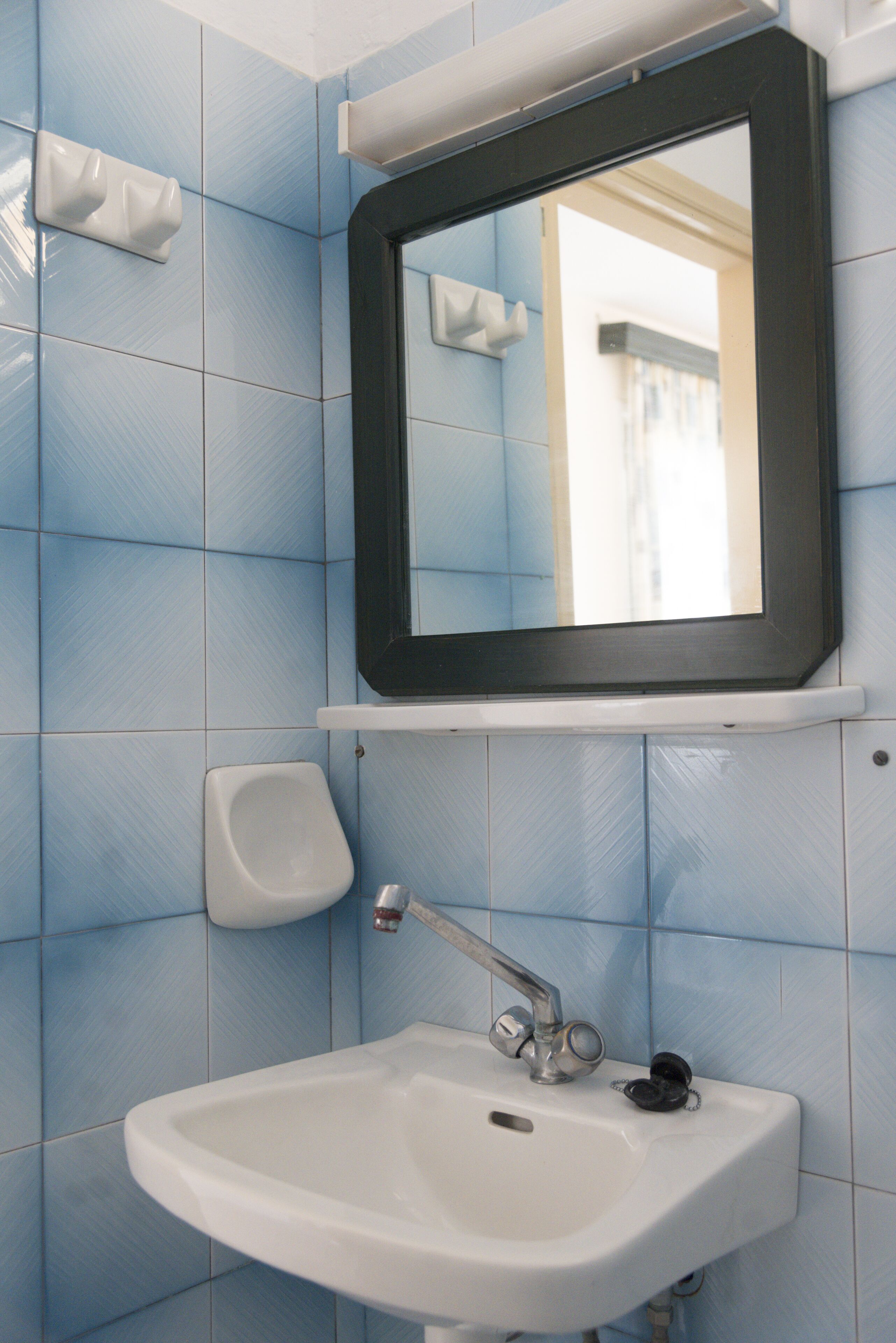 Un bagno con un lavandino bianco, uno specchio e un dispenser di sapone a parete.