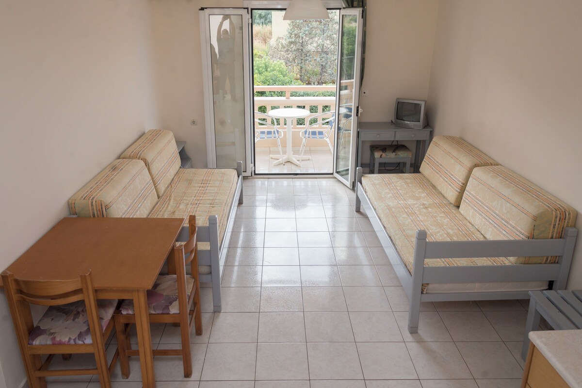 A compact living space with a sofa, a small table, and a TV on a stand.