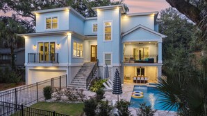 A two-story house with a front porch, a swimming pool, and a fenced backyard.