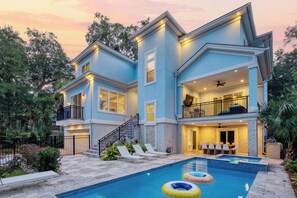 Uma casa de dois andares com piscina, área de estar externa e uma varanda.