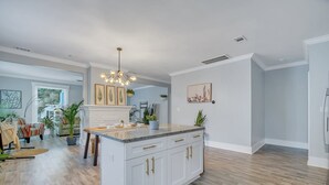 Una cocina amplia con una isla central, armarios blancos y una lámpara moderna.