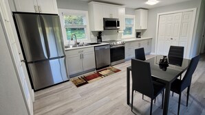 A modern kitchen with stainless steel appliances, a dining area with black chairs, and a view of a garden through the window. - Perfect getaway to magical Damascus (Damascus)