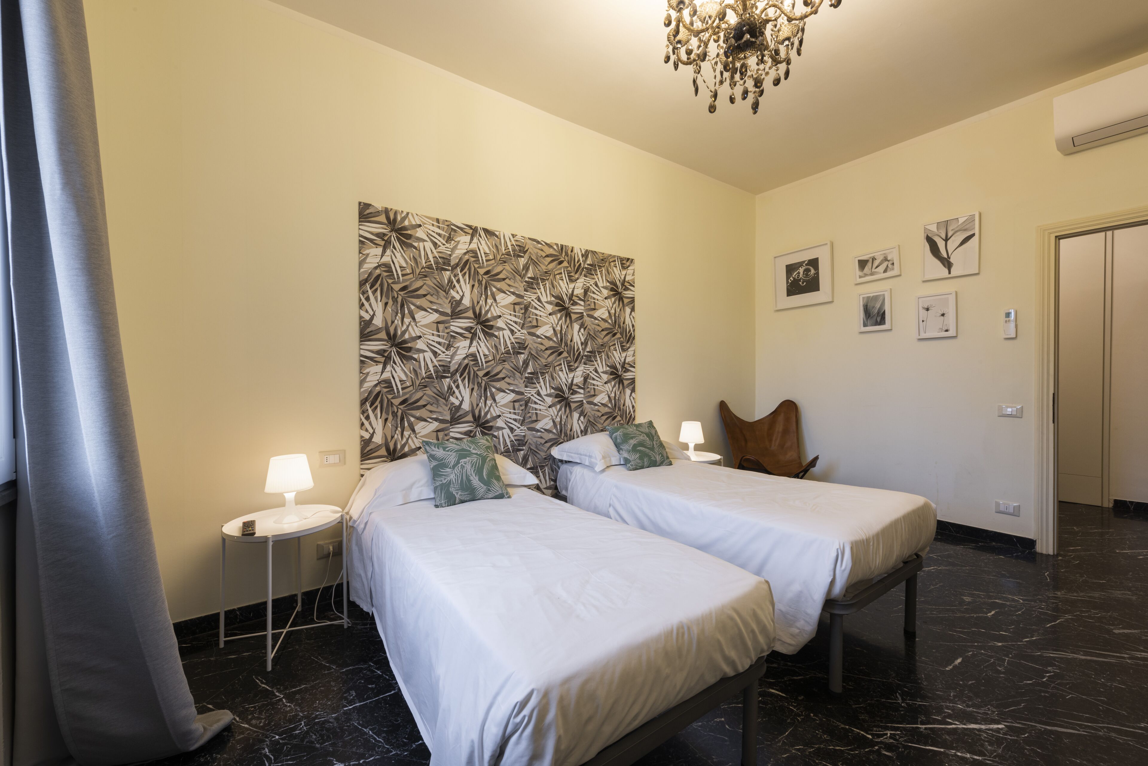 A hotel room with two beds, a large abstract wall art, a chandelier, and a door.