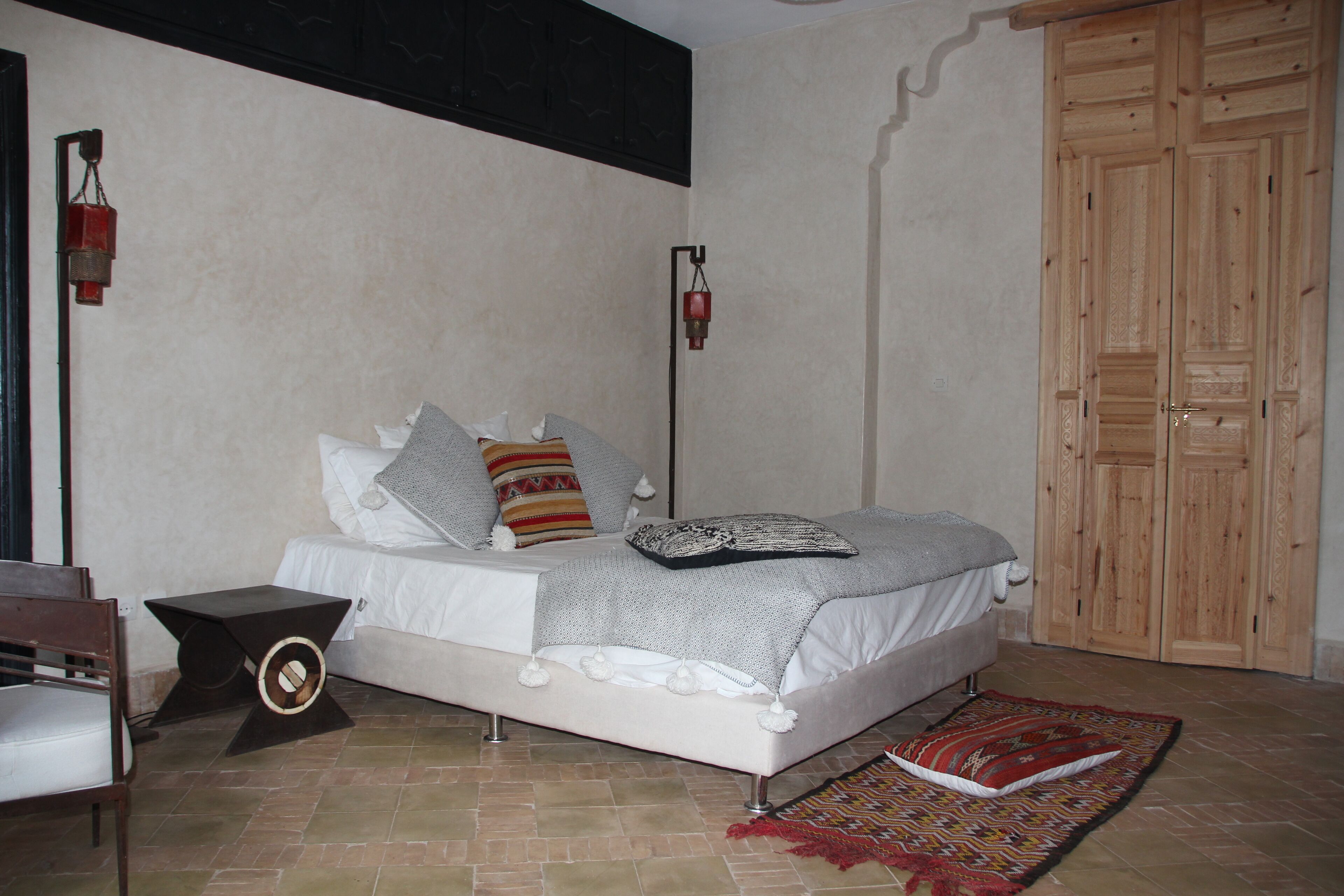 Une chambre à coucher comprenant un lit, des tables de chevet, une armoire et un tapis à motifs.