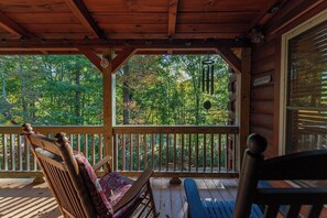 A wooden porch with a view of a forest.