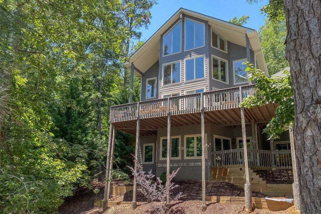 A two-story house with a balcony, surrounded by trees.