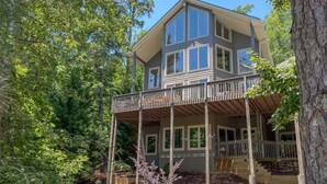A two-story house with a balcony, surrounded by trees. - Blue Star at Rumbling Bald (Lake Lure)