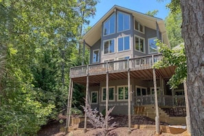 A two-story house with a balcony, surrounded by trees. - Blue Star at Rumbling Bald (Lake Lure)