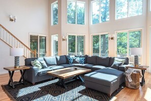 A spacious living room with a large sectional sofa, a coffee table, and a staircase.