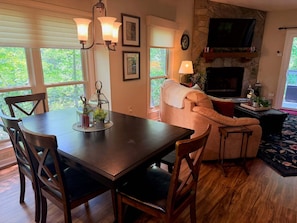 A dining area with a table and chairs, a sofa, a fireplace, and a television.