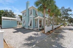 A two-story house with a light blue exterior, a front porch, and a white picket fence.