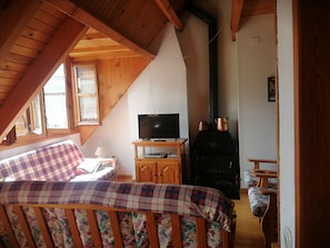 Una habitación acogedora con cama, televisor, chimenea y ventana con vigas de madera.