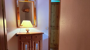 A wooden cabinet with a mirror, a lamp, and a small decorative bowl.