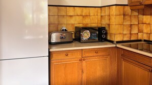 A kitchen with a white refrigerator, wooden cabinets, a toaster, and a microwave.