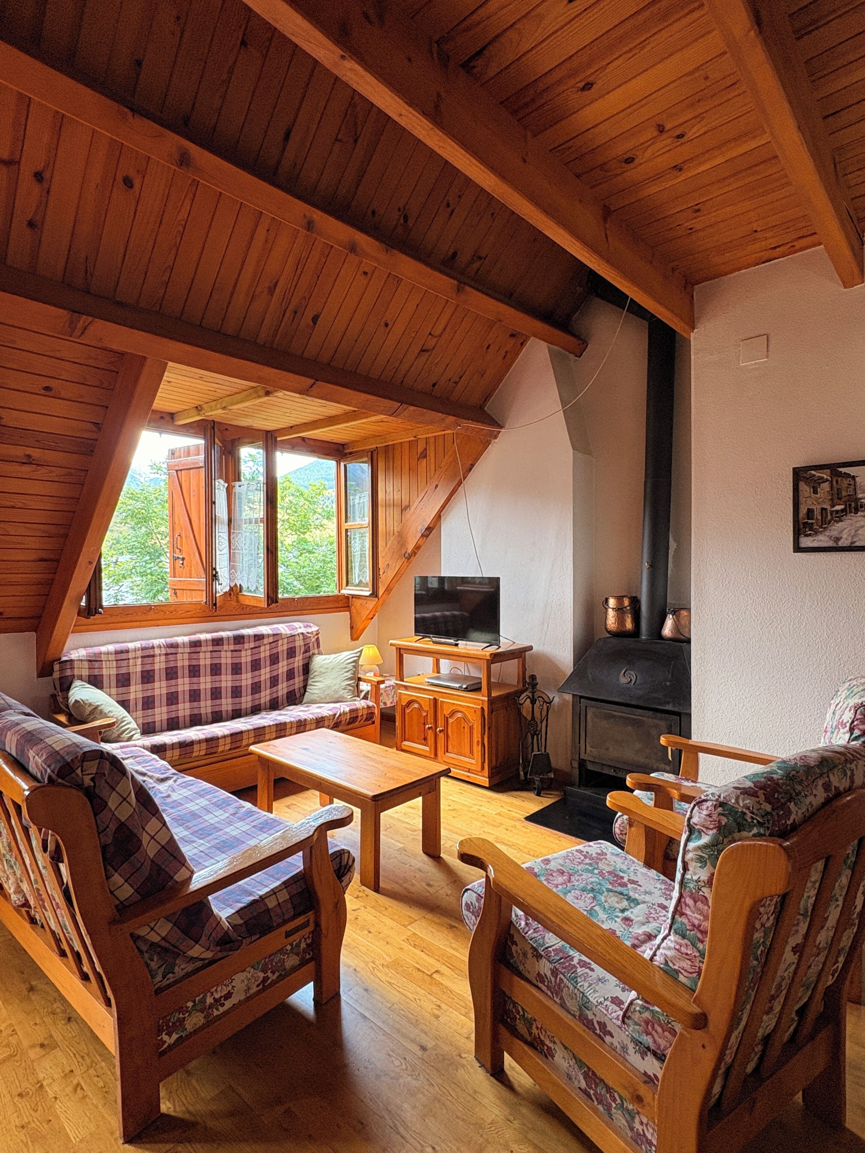 Un salon chaleureux avec un plafond en bois, une cheminée et un téléviseur.