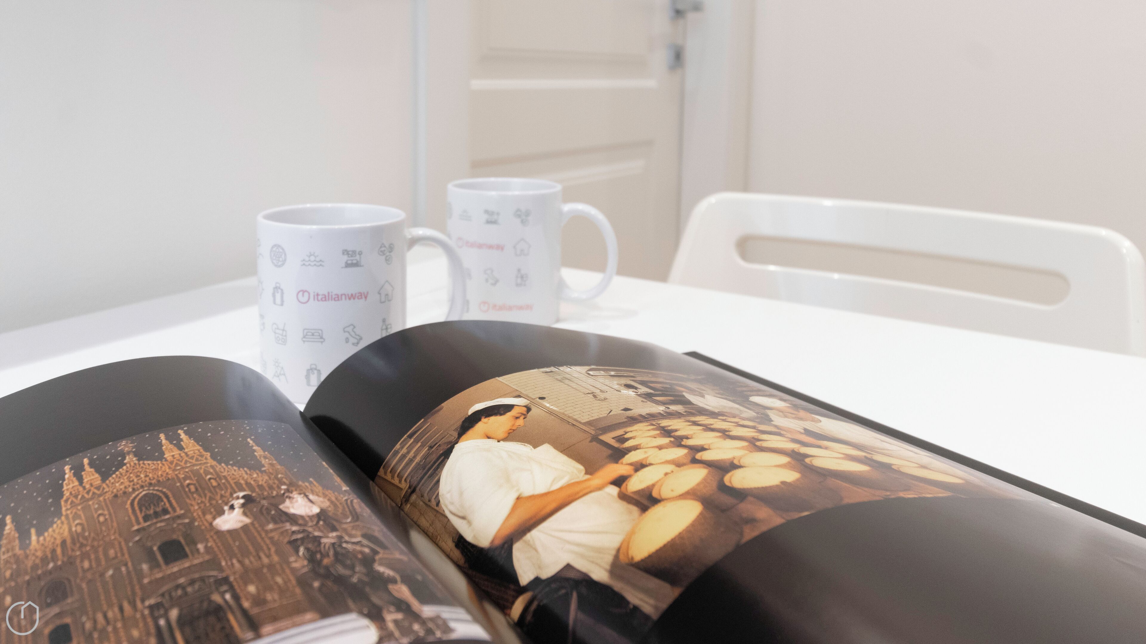 Une table avec deux tasses blanches et un magazine illustré d’un bâtiment historique.