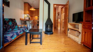 A cozy living room with a sofa, a table, a TV stand, and a wood-burning stove. - North facing apartment - Falcó 12 (Pla de l'Ermita)