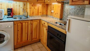A kitchen with wooden cabinets, a washing machine, a dishwasher, a stove, and a refrigerator. - North facing apartment - Falcó 12 (Pla de l'Ermita)