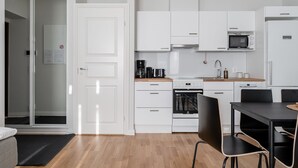 Una cocina moderna con armarios blancos, un microondas, una estufa y un comedor con mesa y sillas.