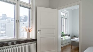 Un dormitorio moderno con un ventanal grande, un radiador y una mesita de noche con una planta.