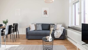 Una sala de estar moderna con un sofá gris, sillas negras, una mesa de centro redonda y una lámpara colgante.