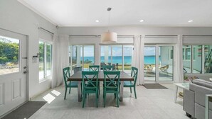Une salle à manger spacieuse avec vue sur l’océan, une cuisine moderne et un balcon offrant également une vue imprenable.