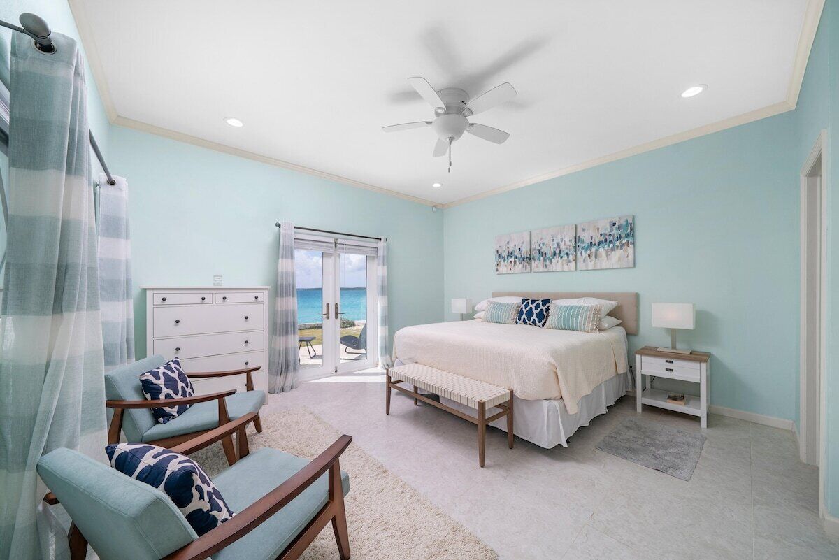 A bedroom with a bed, a desk, a chair, a dresser, and a ceiling fan.
