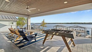 A spacious outdoor area with a foosball table, lounge chairs, and a view of the water.