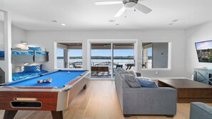 A modern living room with a pool table, a sofa, and a television.