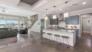 A modern kitchen with a central island, bar stools, and pendant lighting.