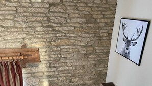 Een stenen muur, een houten kapstok, een lijst met een hertenbeeld en een houten bank.