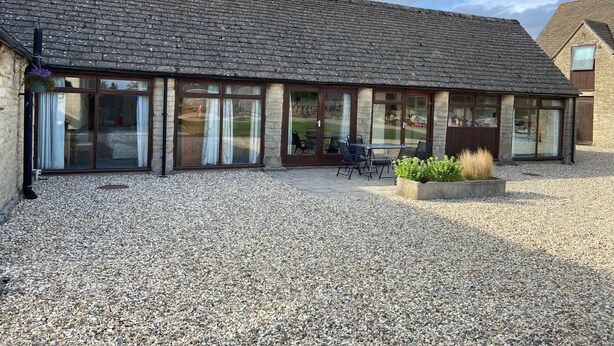 A building with a tiled roof, large glass doors, and a gravel courtyard. - Stable Cottage, Old Mill Farm, Cotswold Water Park (Cirencester)