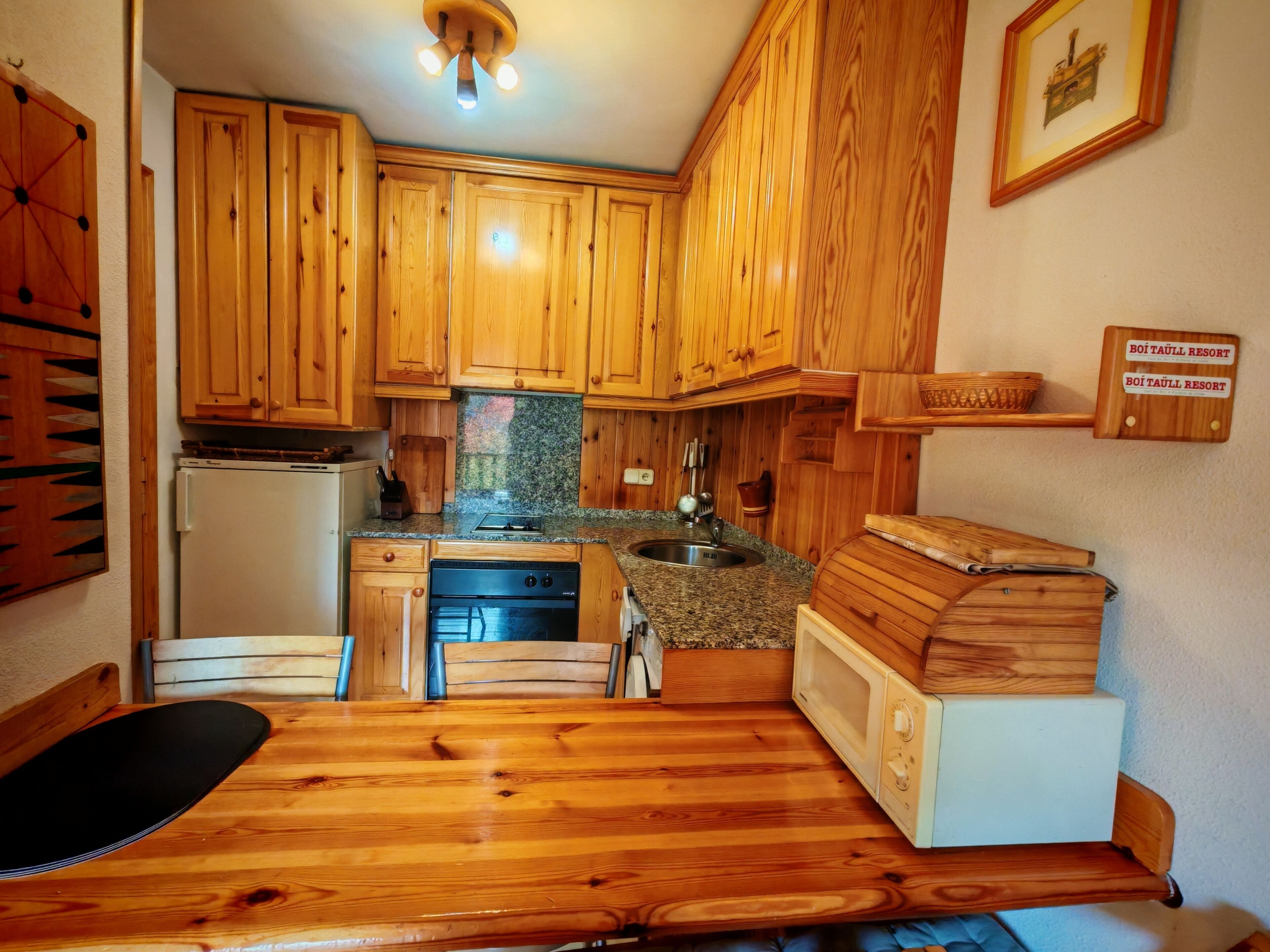 Eine kleine Küche mit Holzausstattung, einem Backofen, einer Mikrowelle und einem Spülbecken.