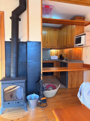 Une cuisine compacte avec des meubles en bois, un four à micro-ondes et un poêle à bois.