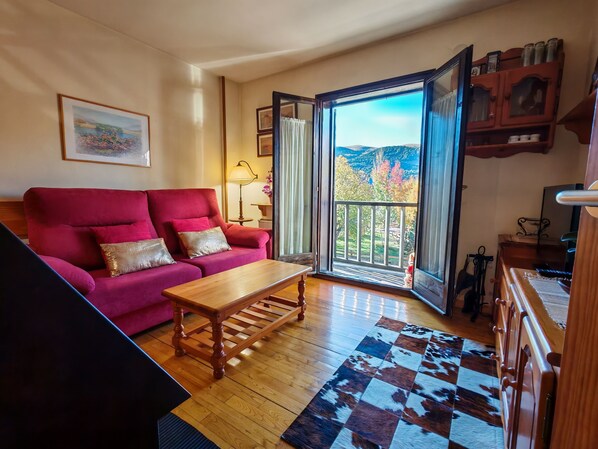 Una sala de estar con un sofá rojo, una mesa de centro de madera y un tapete a cuadros.