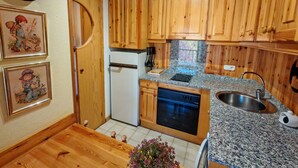 Une cuisine avec des meubles de rangement en bois, un réfrigérateur, un four, un évier et une horloge au mur.