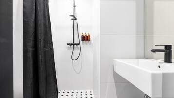 Un baño moderno con ducha, lavamanos e inodoro.