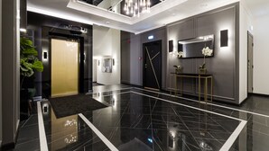 A modern lobby with a black marble floor, a central chandelier, and a reception desk with a plant. - Bob W Tallinn City Centre - Avangard  (Tallinn)
