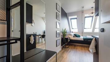 A modern, compact living space with a bed, a desk, and a dining area.