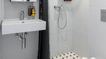 A modern bathroom with a white sink, mirror, and shower.