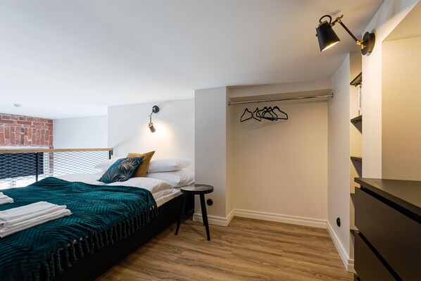 Un dormitorio moderno con una cama, un taburete pequeño, un perchero y un armario.