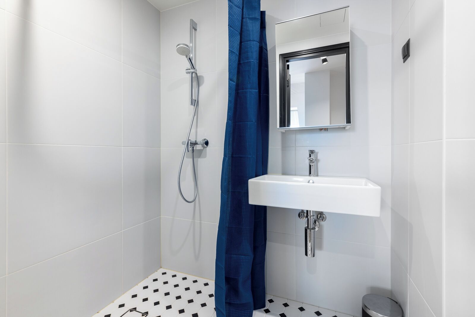 A small, modern bathroom with a shower, a sink, and a mirror.