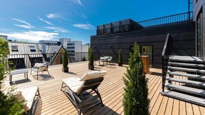 A rooftop terrace with wooden flooring, lounge chairs, and a staircase. - Bob W Tallinn City Centre - Avangard  (Tallinn)